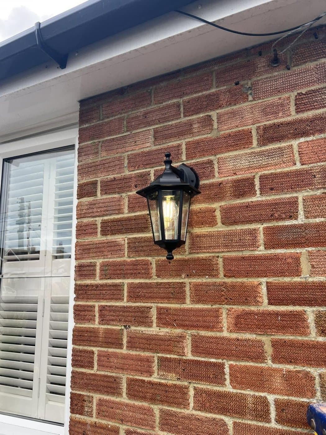 Traditional coach lantern fitted to a brick wall beside a window