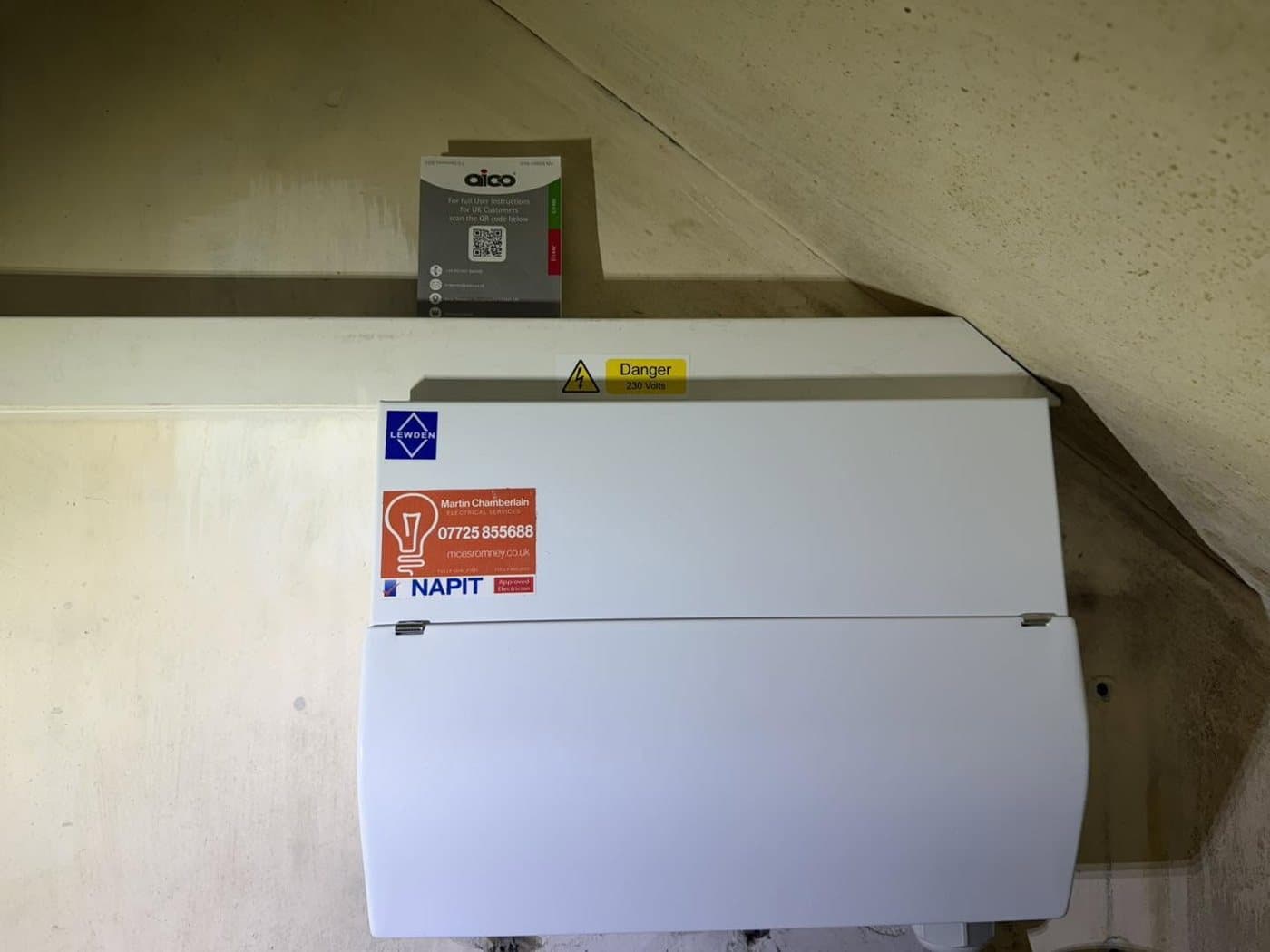 Consumer unit fitted in an under-stairs cupboard with NAPIT and alarm certification labels