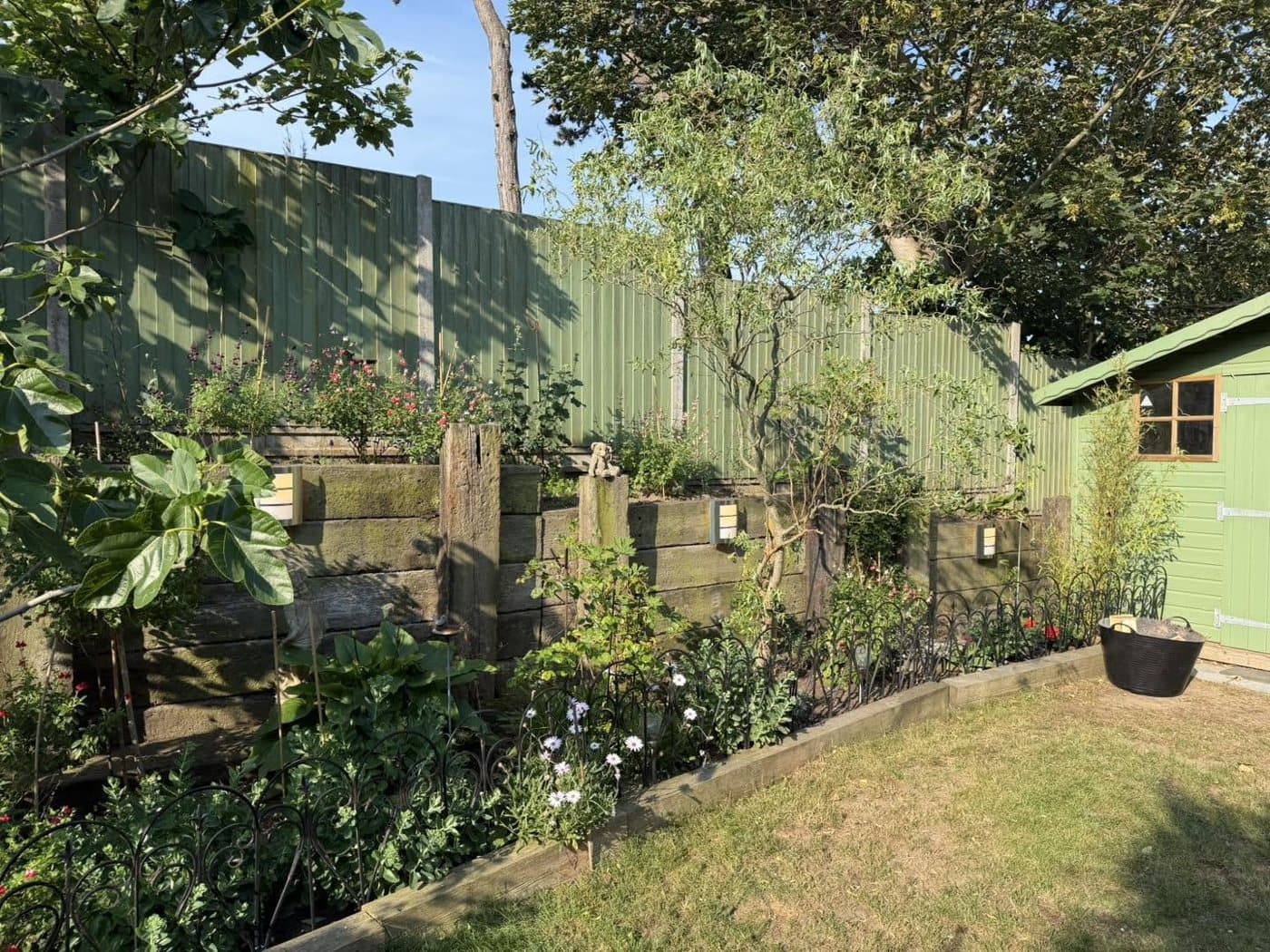 Marsh garden lit at night with spike lighting through the planting and a lit garden room beyond