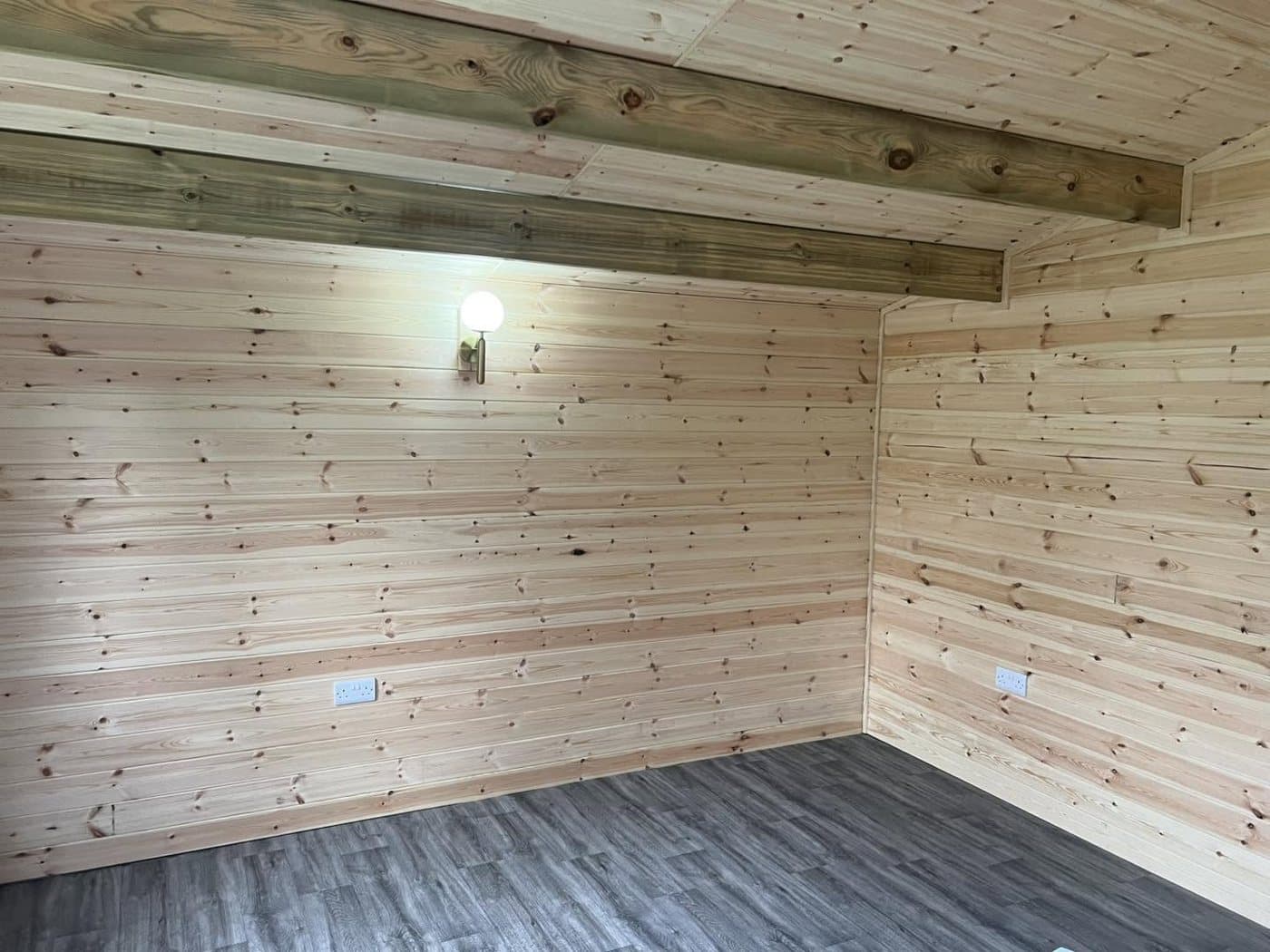 Timber-lined garden room interior with a wall light and power fitted