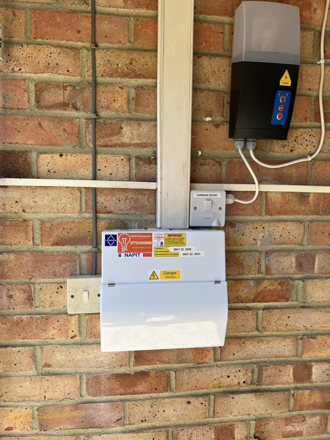 Outdoor socket and security light fitted to a brick wall