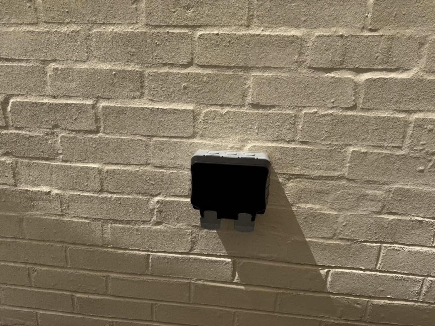 Weatherproof outdoor double socket fitted to a painted brick wall
