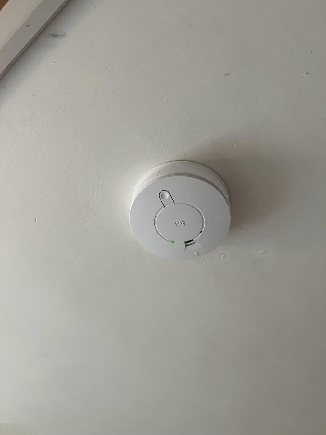 Mains-wired smoke alarm fitted to a ceiling